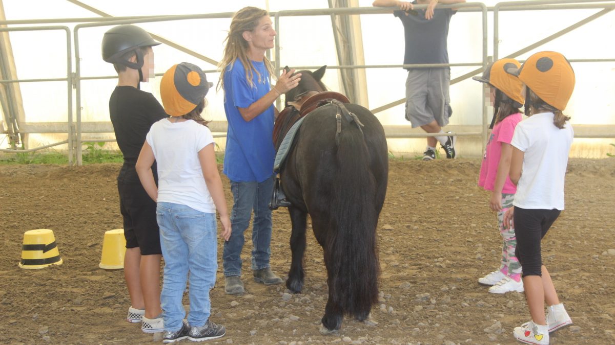 Bambini con un pony durante la lezione di Equitazione Etologica nel maneggio coperto della Scuderia Cento Fiori a Vallecchio di Montescudo, Rimini